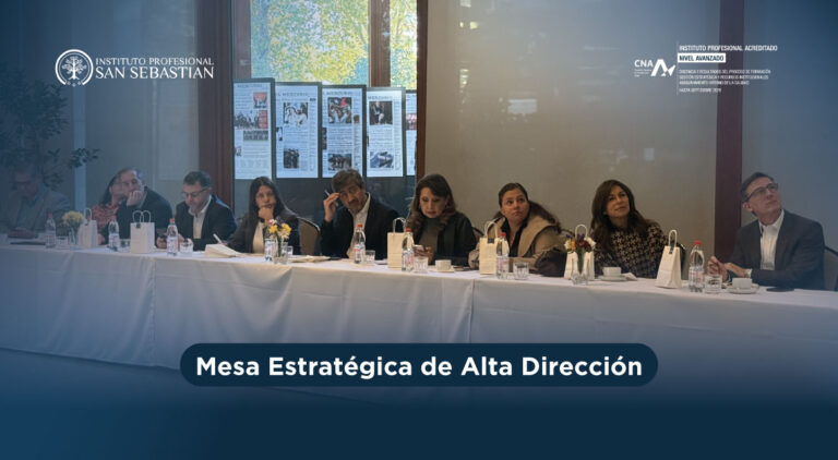 Panel de profesionales sentados en una mesa larga con banderines y botellas, durante una sesión de la Mesa Estratégica de Alta Dirección; logotipos de Instituto Profesional San Sebastián al fondo.