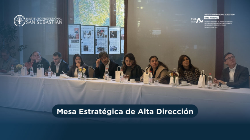 Panel de profesionales sentados en una mesa larga con banderines y botellas, durante una sesión de la Mesa Estratégica de Alta Dirección; logotipos de Instituto Profesional San Sebastián al fondo.